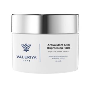 The image shows a jar of "Antioxidant Skin Brightening Pads" from the brand Valeriya Life has a sleek white design. The lid of the jar is silver which adds a touch of elegance to the product. The label features the product name, key ingredients and benefits in a modern, clean font.The jar is placed on a neutral background with soft lighting that highlights its minimalistic, professional appearance.