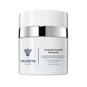 The image shows a jar of "Ceramide Essential Moisturizer" from the brand Valeriya Life. The jar has a clean, white design with a simple label featuring the product name and logo in elegant, bold text. The lid of the jar has a silver ring, adding a sophisticated touch. The jar is placed on a light-colored, neutral background, showcasing the minimalist and professional packaging of the product. The jar's label also features key product ingredients.